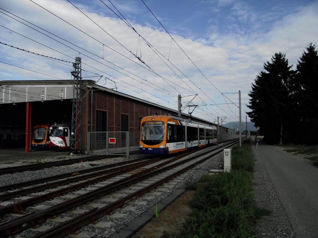 Eine RNV Variobahn (RNV6) auf der Linie 5 der OEG in Edingen. In der Wagenhalle stehen ein Dwag GT8 auch von der OEG und ein HSB RNV8 