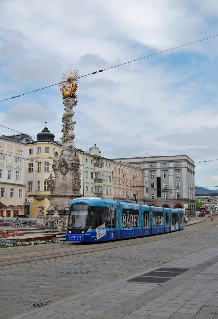 Eine Strassenbahngarnitur der Linie 1 passiert am 06.05.2013
die Dreifaltigkeitssule am Hauptplatz in Linz.
