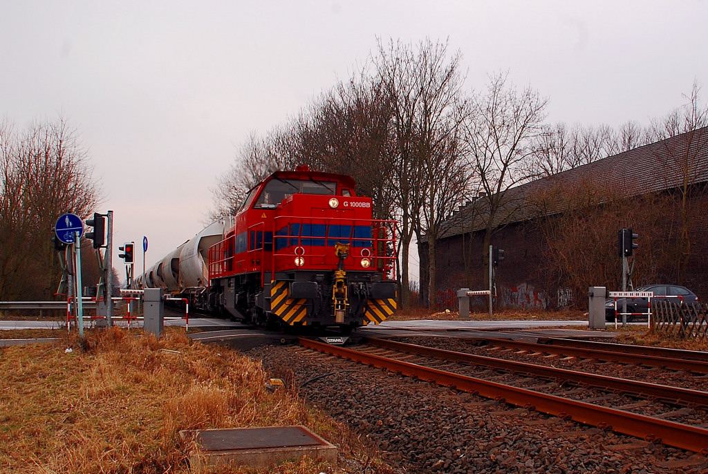 Eine Vossloh MAK G1000BB mit leeren Silowagen, vermutlich von einem der RWE Braunkohlekraftwerken abgeholt, ist hier am Bahnbergang Hemmerder Weg an der L142 zu sehen. 12.2.2012