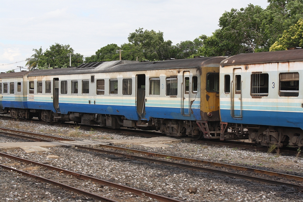 Eingewickelt ist der กซข.1037 (กซข. = BPD/Bogie Power Diesel Railcar With Driving Cab, Hitachi/Nippon Sharyo, Bauj. 1971) am 13.Juni 2011 auf dem Weg vom Bahnhof ins Depot Nakhon Ratchasima.