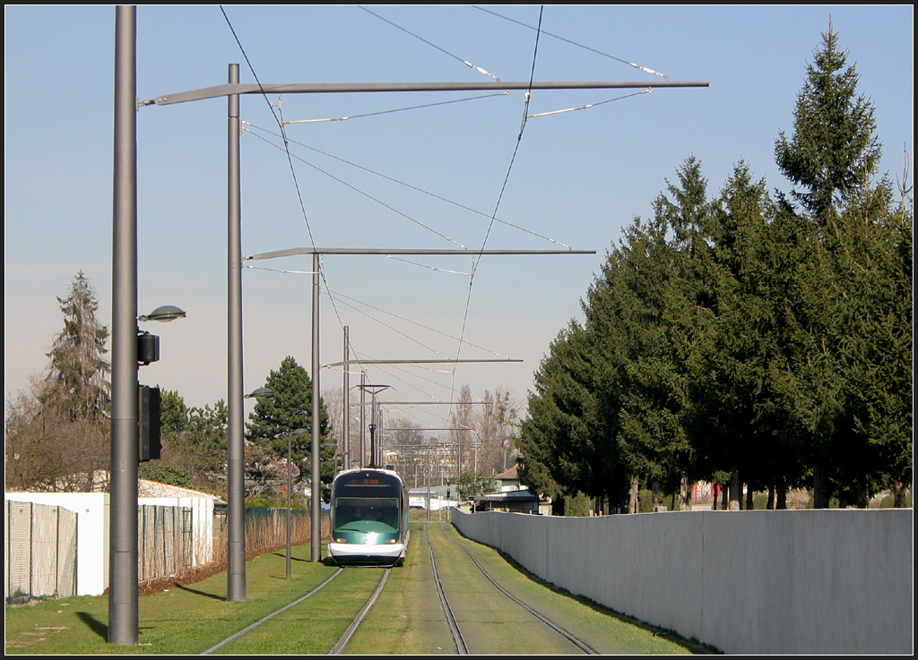 Elegante Masten - 

Im Quartier Neuhof in Straßburg verläuft die Trasse der Linie C in diesem Abschnitt nicht auf der Straße sondern hinter der Bebauung entlang eines Friedhofes. Die Oberleitungsmasten und Ausleger sind außerordentlich elegant im Design. Die neuen französischen Straßenbahnen verwenden in der Regel Einfachfahrleitungen, im Gegensatz zu den in Deutschland üblichen eisenbahnmässigen Hochkettenfahrleitungen. Vorne machen die Gleise eine Kurve, ich stehe rechts neben diesen. Die Strecken der Linien C und D im südöstlichen Bereich von Straßburg gingen am 25. August 2007 in Betrieb. 

06.03.2008 (M)