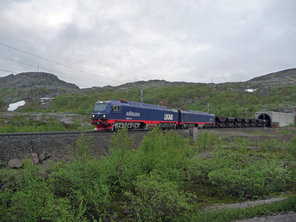 Erzzug der LKAB auf dem Bjrnfell bespannt mit einer IORE-Lok der neuesten Generation (Nr. 110  Bjrkliden  und 109  Abisko ), als Leerzug Richtung Kiruna. Zug verlsst gerade einen Tunnel in Richtung schwedischer Grenze. Die Strecke wurde hier vor Jahren vllig neu trassiert, um die stark in die Jahre gekommene Norddalsbrua umgehen zu knnen. Aufnahme vom 05.07.2010