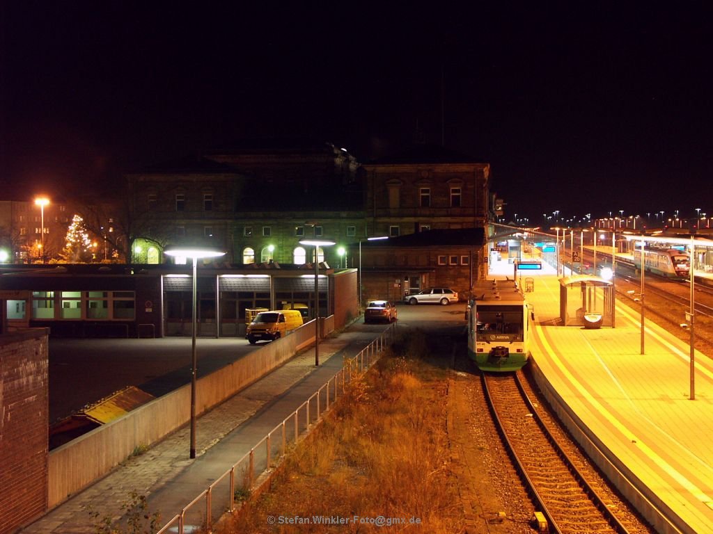 Es weihnachtet auch ohne Schnee am Hofer Hbf. Erkennbar am grossen Weihnachtsbaum mit Beleuchtung auf der Strassenseite links. Die VGB mit dem Sprinter muss noch warten bis zur n�chsten Abfahrt. Personal ist an Bord, alle Lichter sind aus.... Der Desiro der VGB rechts f�hrt grade weiter, knapp noch erwischt...