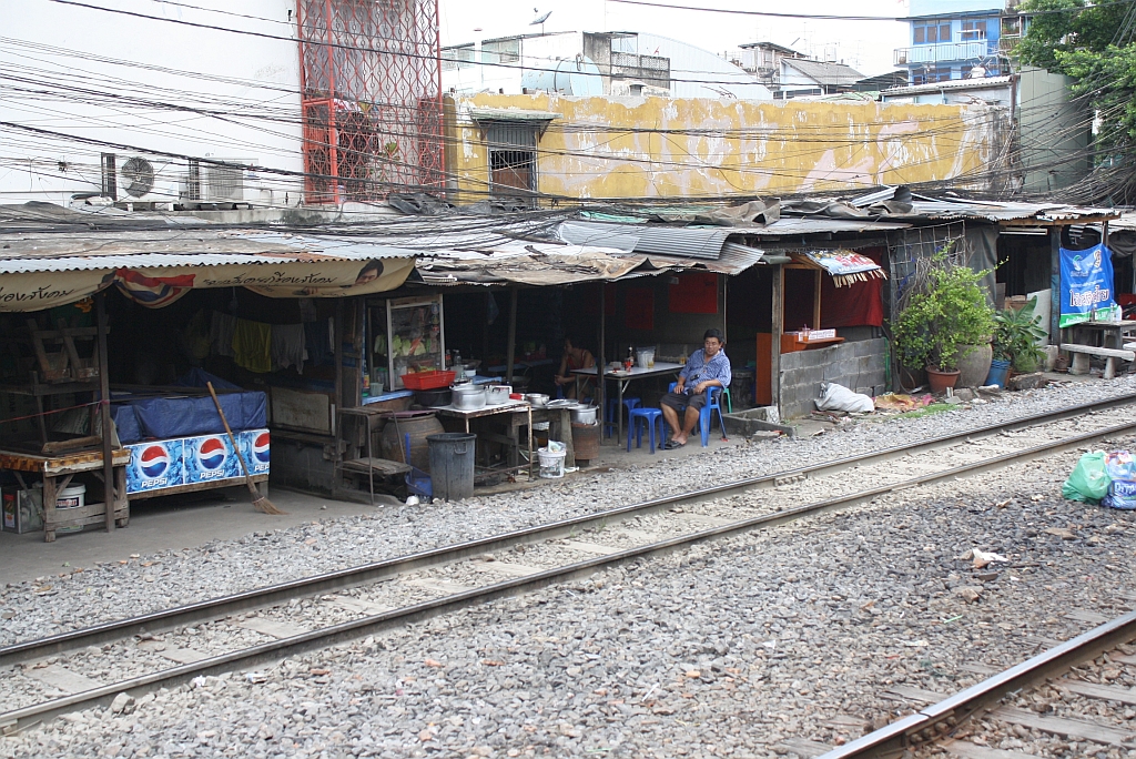 Etwa 200m vor dem Einfahrtsignal des Bf. Hua Lamphong in Bangkok befindet sich dieses Lokal, das die drei stark befahrenen Streckengleise berhaupt nicht kmmert. So etwa mssen Alptrume europische Ordnunghter aussehen. 24.August 2010.
