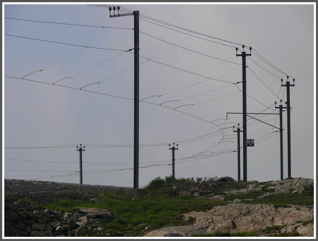 Fast wie ein Spinnennetz hngt die Fahrleitung der Berninabahn an den Masten entlang des Lago Bianco. (14.07.2010)