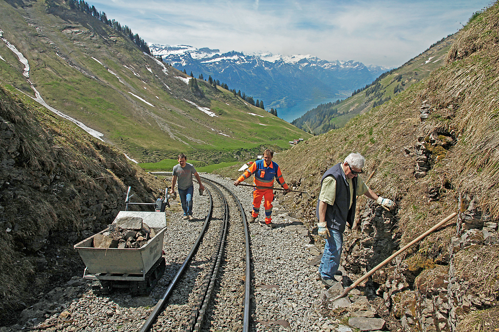 Freiwilligen-Arbeit bei der BRB (jeder konnte mitmachen): Den Khmatt-Tunnel (92 m) und die Khmatt-Galerie (40 m) haben wir bereits kontrolliert und gereinigt. Nun gehen die Arbeiten weiter im Khmatt-Einschnitt. Das kleine Raupenfahrzeug mit Mulde leistet gute Dienste: wir fllen den Container mit Steinen, Schutt, Erde und sten. Dann fahren wir zur nchst gelegenen Stelle und kippen das Material aus. Sonst mssten wir die schweren Steine talwrts tragen und hinunterwerfen. Russlan aus Russland, Daniel Blatter vom BRB-Baudienst, Peter aus Solothurn und ich legen Hand an. Aufnahme vom 08. Juni 2013, 11:35