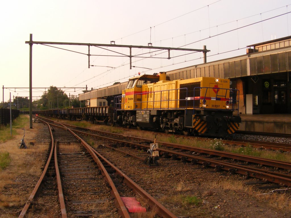 G 1206 Strukton Rail 303007 called Demi with prorail-Kls-train leaves Naarden-Bussum after having passed by some passengertrains in the south direction the evening of 20/6/12 while the driver has put on the warning lights on the cab for a salute to his photografer :-)

STANDORT NICHT IM GLEISBEREICH I am staying on the parking which was a former railloading but taking the picture trough a Abrasterung.