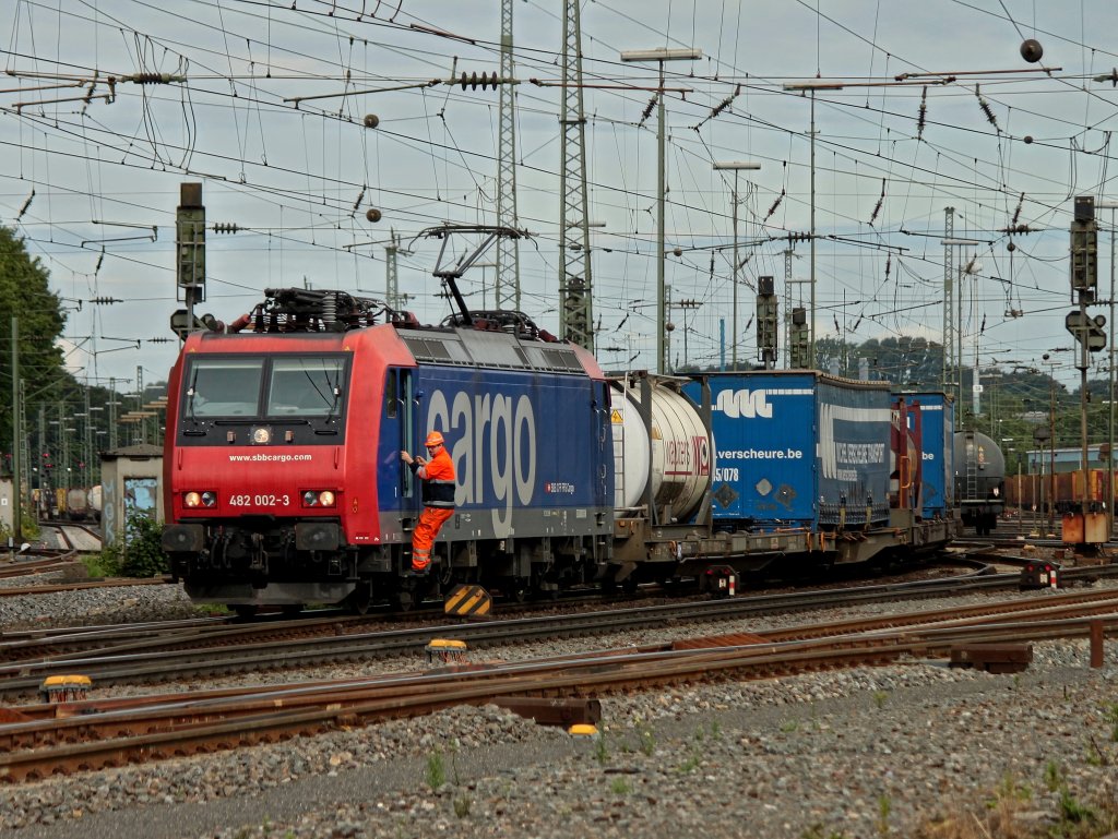 Ganz langsam fhrt 482 002-3 mit einem Containerzug am Haken am 19.07.2011 aus Aachen West, der SBB Mitarbeiter auf der Trittstufe mu hinter der Weiche abspringen.