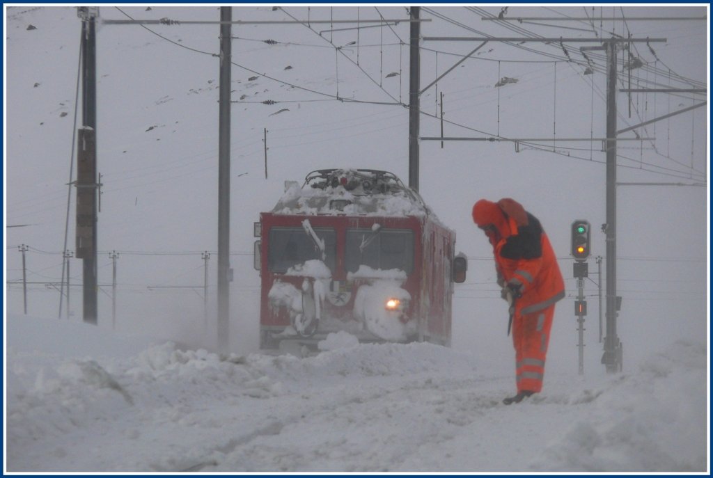 Gem 4/4 801 macht sich aus dem Staub, whrend der Arbeiter versucht mit einem Pickel den festgepressten Schnee, der hart wie Beton ist, aus einer Weiche zu entfernen. (01.12.2009)