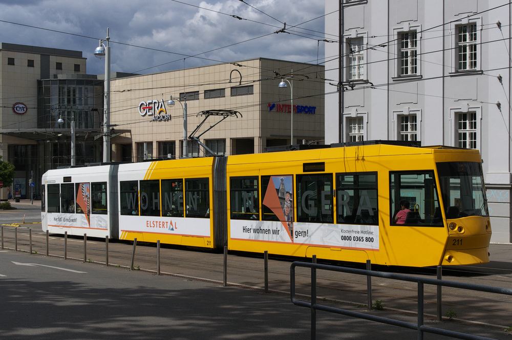 Getauft auf den Namen einer Fotoknstlerin - 

Triebwagen 211, NGT8G, ist eines derjenigen Fahrzeuge, das den Namen eines (r) Persnlichkeit aus Gera trgt.

Aenne Biermann (1898 - 1933), international bekannte Fotoknstlerin und
Vertreterin der Neuen Sachlichkeit, lebte von 1920 bis zu ihrem frhen Tod in Gera, ihre jdische Familie emigrierte nach Palstina.

Tw 211 wird gleich den  Zentralen Umsteigepunkt  Heinrichstrae erreichen und ist gerade unter dem  Elster Forum  hindurch gefahren..

Gera am 07.08.2012