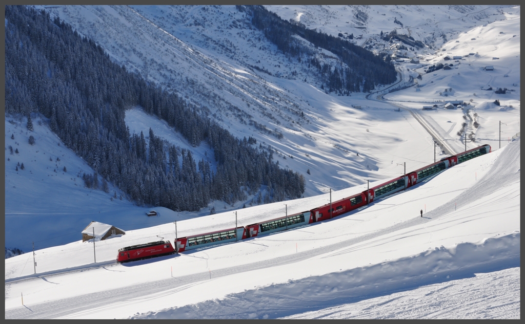 Glacier Express 903 mit HGe 4/4 108 bremst langsam nach Andermatt hinunter. Im Hintergrund ist Hospenthal zu sehen. (10.01.2012)