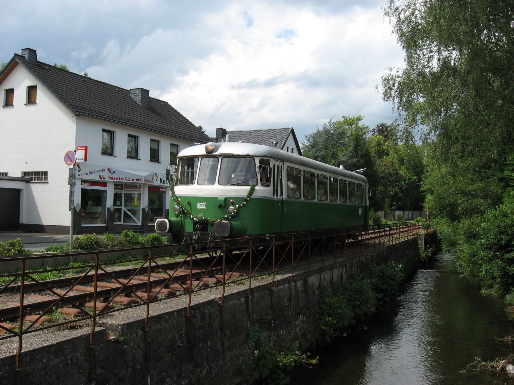 grn-weier Rhein-Sieg-Eisenbahn Schienenbus am 01. August 2010 kurz vor dem Bahnbergang in Hellenthal.