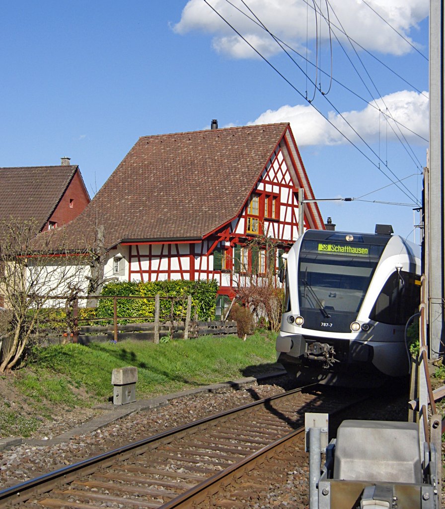 Haus und Bahn - Die Seelinie schlngelt sich in Berlingen zwischen den Husern des beschaulichen Ortes am Bodensee hindurch. GTW 787-7 hat als S 8 von Rorschach kommend den Bahnhof mit Ziel Schaffhausen gerade verlassen (13.04.2013).