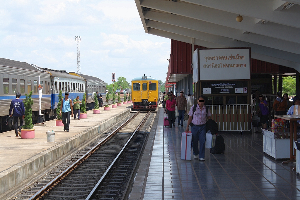 Hausbahnsteig des Bf. Nong Khai am 17.Juni 2011. Im Kiosk mit dem groem weissen Schild befindet sich die Immigration fr Reisende nach bzw. von Laos. Im Hintergrund der zweimal tglich nach Thanaleng (Laos) pendelde Triebwagen der Reihe RHN, sowie links der Wagensatz des soeben angekommenen EXP 69.