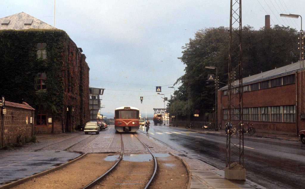 Helsingør am 30. September 1974: Ein Triebzug der HHGB, Helsingør-Hornbæk-Gilleleje-Banen, fährt am Verwaltungsgebäude der Schiffswerft vorbei. - Auf dem Gelände der Werft gibt es heute ein Werftsmuseum (Helsingør Værftsmuseum).