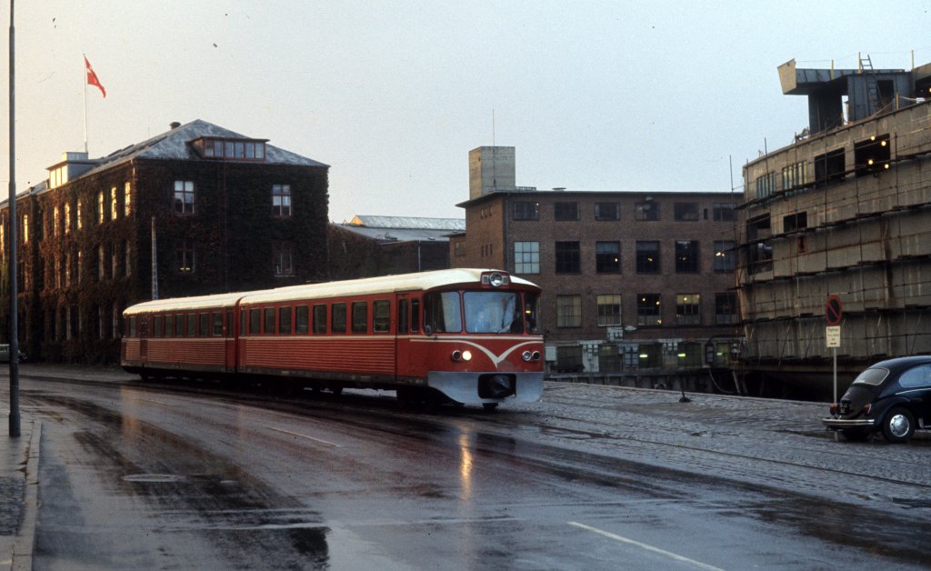HHGB, Helsingør-Hornbæk-Gilleleje-Banen: Triebzug (Ys + Ym) Havnegade / Helsingør Værft (: Werft) am 30. September 1974. - Die Schiffswerft, die 1882 gegründet worden war, musste 1983 wegen eines leeren Auftragsbuchs schliessen. Die Werft - damals der grösste Arbeitgeber in Helsingør - baute u.a. viele der DSB-Fährschiffe, die damals zwischen den Landesteilen, zwischen Dänemark und Deutschland und zwischen Dänemark und Schweden fuhren. Rechts im Bild ist eine neue Fähre im Bau. 