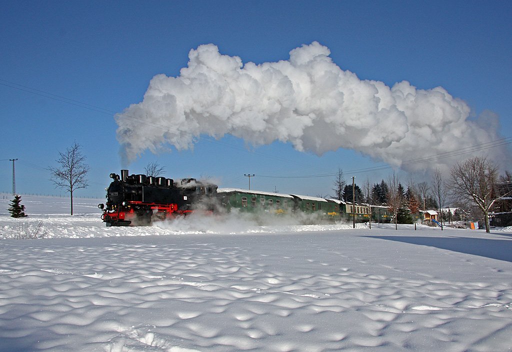 Hier befindet sich 99 771 mit ihrem Zug im oberen Teil von Neudorf unterhalb des Skihanges. Auch hier bieten sich hervorragende Wintersportbedingungen.