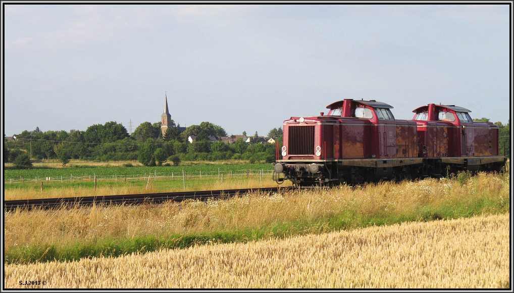 Hinein fhrt der Blick zuerst auf die Landschaft,die Dorfkirche bei Wieskirchen,
whrend gleich das Doppelgespann aus zwei V 100. aus dem Sichtfeld verschwindet.
Abendliche Sommerszenerie eingefangen bei Euskirchen im Juli 2013.