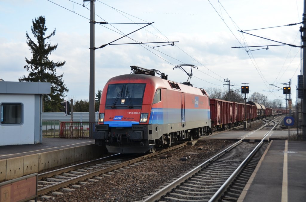  Hochwasser-Taurus  1116 048 ex Rail Cargo Hungaria  fahrt mit einem gemischten Gterzug durch die Haltestelle Rannersdorf-Lanzendorf in Richtung Wien. 18.2.2012