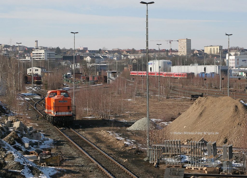 Hof Hbf am 25.Februar 2011. Das war Tag der DR V 100 in dem Bahnhof. Bei genauem Hinsehen erkennen wir 5 solche Maschinen auf diesem einen Bild. Rechts vorne liegen vorgefertigte Bewehrungsteile für Mastfundamente der künftigen Oberleitung, die Locon-Lok ist die Bauzugmaschine für diese Arbeiten.