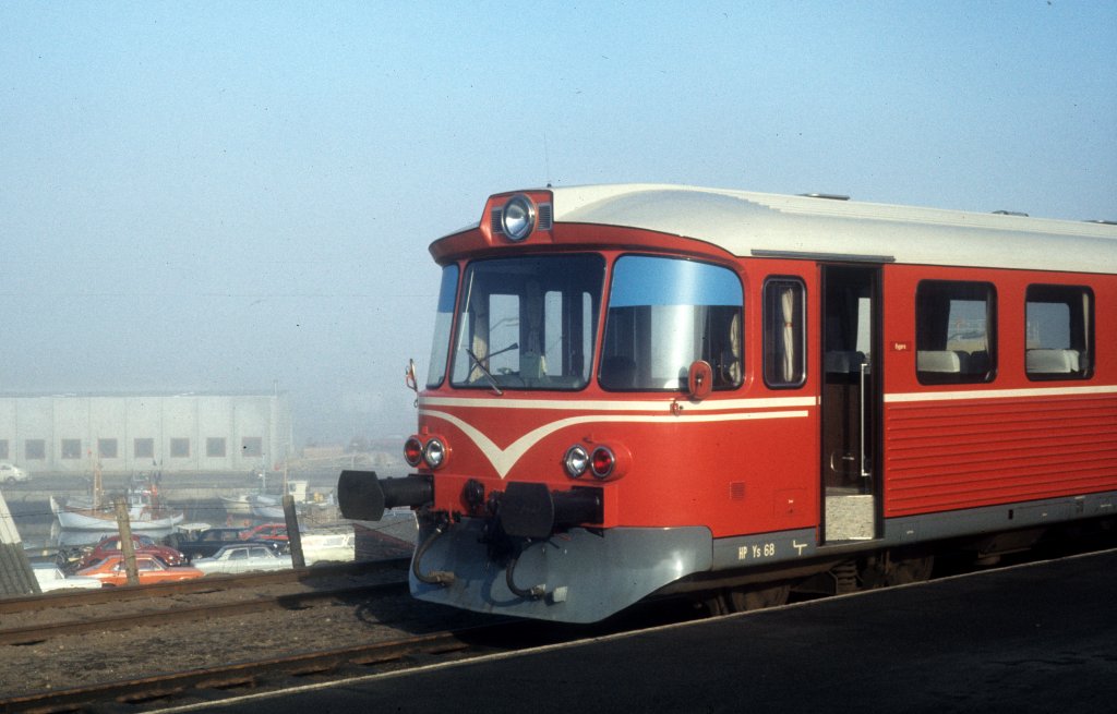 HP, Hjørring Privatbaner (Hirtshalsbanen): Ys (Steuerwagen) 68, dessen vorderen Teil man auf dem Foto sehen kann, wurde 1974 von der Waggonfabrik Uerdingen gebaut. Der Steuerwagen hält am 24. Februar 1975 am HP-Bahnhof Hirtshals. - Unterhalb des Bahngeländes ist ein kleiner Teil des Hirtshalser Hafens zu sehen.