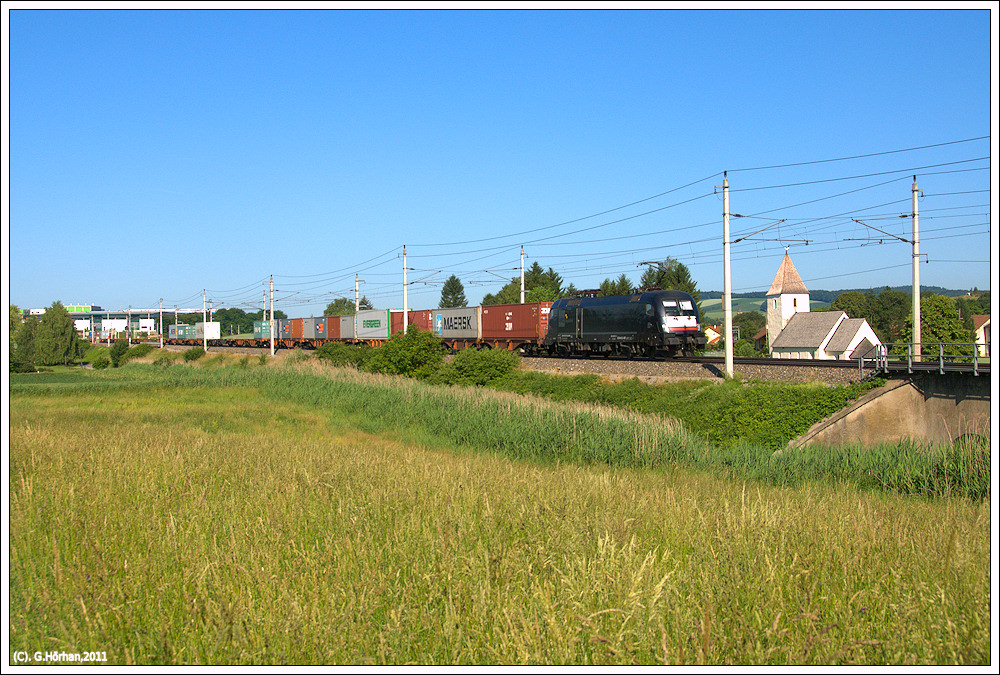 Ich war wieder einmal an der Westbahn unterwegs: ES 64 U2 067 mit Containerzug hat vor kurzem Bheimkirchen durchfahren und passiert das romanische Kircherl mit dem schiefen Turm in Lanzendorf bei Kirchstetten, 7.6.2011