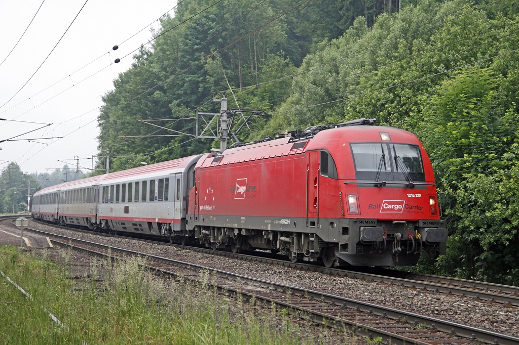 Im Frhnebel zieht die 1216 228 den EC172 (Villach - Hamburg) am 17.06.2013 durch Langenwang.