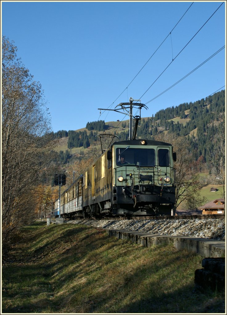 Im goldenen Herbst 2010 fährt die goldene Schokoladen GDe 4/4 ihre neuen  Boîte de Biscuits/Keks-Dosen   am 5. Nov. 2010 als Regionalzug 2224 durch ein Wäldchen bei Saanen Richtung Gstaad. 