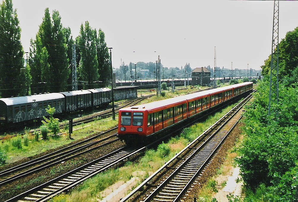 Im Juni 1998 fuhr ein Triebzug der BR 485 kommend aus Berlin-Zentrum in den Hp. Pankow-Heinersdorf ein. Links ein DR-Hilfzug, abgestellt im ehemaligen Rangierbahnhof Pankow.
Scann.