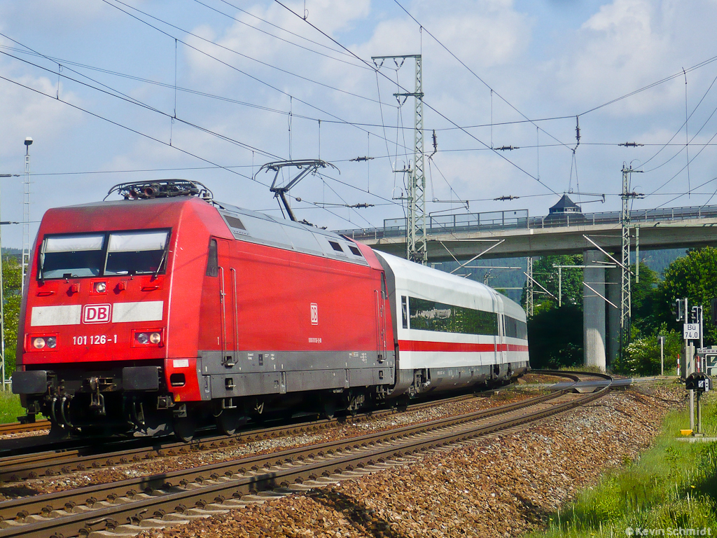 Im morgendlichen Sonnenschein durchfährt ICE 915 mit 101 126-1 an der Spitze in Kürze den Bahnhof Saalfeld (Saale). Der nächste Halt ist Nürnberg Hbf, den die ehemalige MET-Garnitur in ca. 2 Stunden erreichen wird. (28.05.2011)