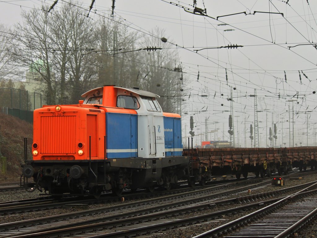 Im Nebel des 02.03.2012 fhrt 212 256-2 der Nordbayerischen Eisenbahn mit einem mit alten Schwellen und Schienen beladenen Niederbordwagenzug aus Aachen West Richtung Kln.