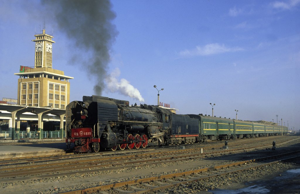 Im Winter 1997 lieen sich noch einige reagulre Einstze von Dampflokomotiven der Klassen QJ und JS auch im Raum Baotou (chin. Provinz Innere Mongolei) beobachten. Morgens und Abends wurden auf der Ringbahn um die Stadt und ihren ausgehenden Strecken teils schwere Personenzge mit Dampfloks befrdert.

Bekannt war die Stadt Baotou auch durch ihr groes Stahlkombinat, welches noch bis vor wenigen Jahren Dampflokeinstze (Sy) bot.

Hier steht QJ 6519 mit ihrem Personenzug abfahrbereit im Bahnhof Baotou Dong.

Dez. 1997 (Diascan)