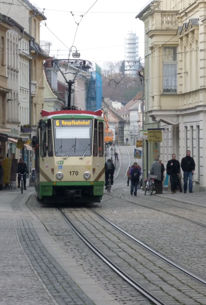 In den Jahren 1997 und 1998 wurden zehn Brandenburger KT4D in Mittenwalde mit einem Niederflurmittelteil ausgestattet. Die jetzt als KTNF6 bezeichneten Fahrzeuge bestreiten zusammen mit vier Triebwagen vom Typ MGT6D den Gesamtverkehr. F�r Sto�zeiten sind auch nicht umgebaute KT4D vorhanden. Das und noch mehr kann man in dem kleinen (aber feinen) Stra�enbahnmuseum am alten Betriebshof Bauhofstra�e erfahren (ge�ffnet Donnerstag und Samstag). 
Auf dem Bild f�hrt der erste Brandenburger KT4D als KTNF6 170 durch die Hauptstra�e und erreicht gleich die gleichnamige Haltestelle. Brandenburg/Havel, 2009-11-12.