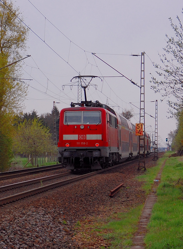 In Richtung Rheydt schiebt die 111 158-2 eine RE4 kurz hinterm Bahn�bergang Herrather Linde am Abend des 17.4.2012............