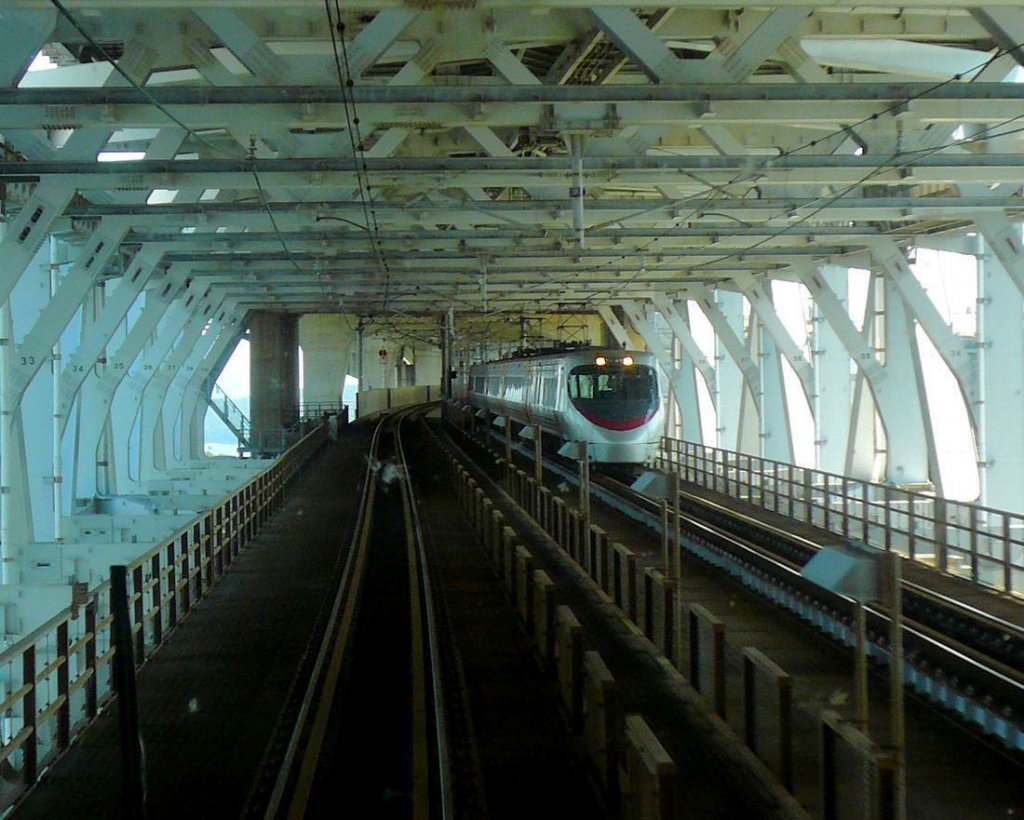 JR Shikoku Serie 8000 hoch über dem Meer auf der riesigen Seto-Brücke. Diese Brücke (eröffnet 1988) stellt erstmals eine Landverbindung zwischen der japanischen Hauptinsel und der Insel Shikoku her; insgesamt 13km lang, wovon ca. 9,4km Brücke (unter Nutzung kleiner Inselchen in der Inlandsee unterteilt in 10 Einzelbrücken). 17.September 2009. 