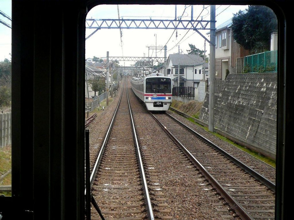 Keisei-Konzern, Serie 3700: Unterwegs (bei Kaijin) kreuzt Zug 3841 (mit Frontwagen 3848) am 4.März 2010. (Aufnahme durch die verglaste Führerstandrückwand eines Gegenzugs.) 
