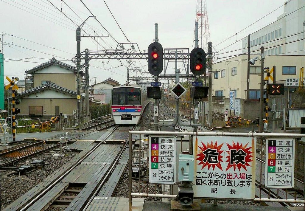 Keisei-Konzern, Serie 3700: Zug 3791 verlässt den Bahnhof Narita Stadt. Am Ende des Bahnsteigs sind Tafeln, welche die 6 Zugskategorien signalisieren, und Warnungen, den Bahnhof keinesfalls vom Bahnsteig aus zu verlassen, angebracht. 22.November 2009. 