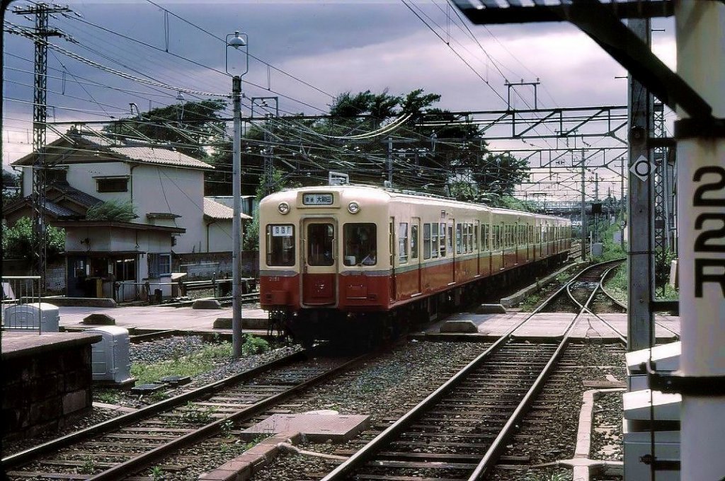 Keisei-Konzern, Serien 3000-3200: Zwischen 1958 und 1967 wurden 204 Wagen dieser neuen Nachkriegsbauart in Betrieb genommen; sie befuhren auch eine der U-Bahnlinien in Tokyo (Städtische U-Bahn Asakusa-Linie). Ein Blick aufs Dach zeigt, dass sie trotz der extrem schwülen Sommerzeit noch keine Klimaanlage hatten. Hier fährt ein Zug mit Endwagen 3151 durch Keisei Tsudanuma, 19.Juli 1979. 
