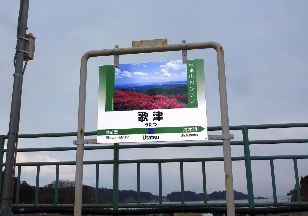 Kesennuma Linie, Bahnhof Utatsu: Noch immer prangt die farbenfrohe Stationstafel auf dem Bahnsteig, vor dem es keine Schienen mehr gibt. Solche Stationstafeln sind typisch für die Kesennuma-Linie mit ihrem (früheren) touristischen Potential; wie alle Stationstafeln in Japan werden stets auch die beiden Nachbarstationen zur Orientierung genannt. 19.Februar 2013.  