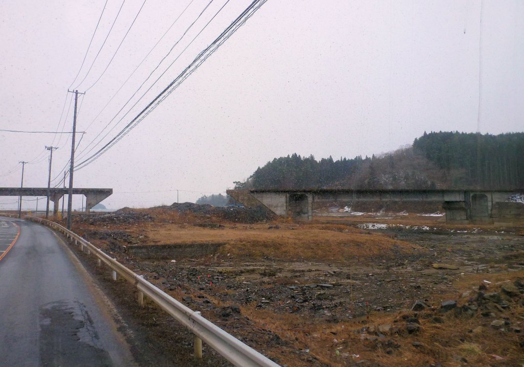 Kesennuma-Linie, die Brücke von Shizuhama: Auf dieser Brücke befand sich bis zum Tsunami der Bahnhof dieses Dorfes, von dem nichts mehr zu sehen ist ausser den Häuserfundamenten. Bild bei leichtem Schneetreiben aus dem Bahnersatz-Bus. 15.Februar 2013. 