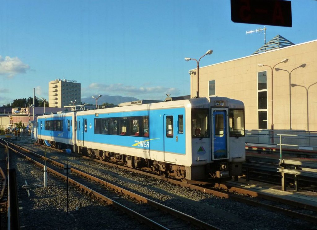 KIHA 101: Die beiden Wagen KIHA 101-12 und 4 warten in Sagae auf ihren Einsatz. 18.Oktober 2011. Diese Wagen tragen eine Aufschrift in etwas japanisiertem Englisch  Fruits Liner , da sie durch ausgedehnte Obstplantagen (Aepfel, Birnen, Kirschen, Kaki-Früchte, Kastanien, Trauben u.a.m.) fahren. 