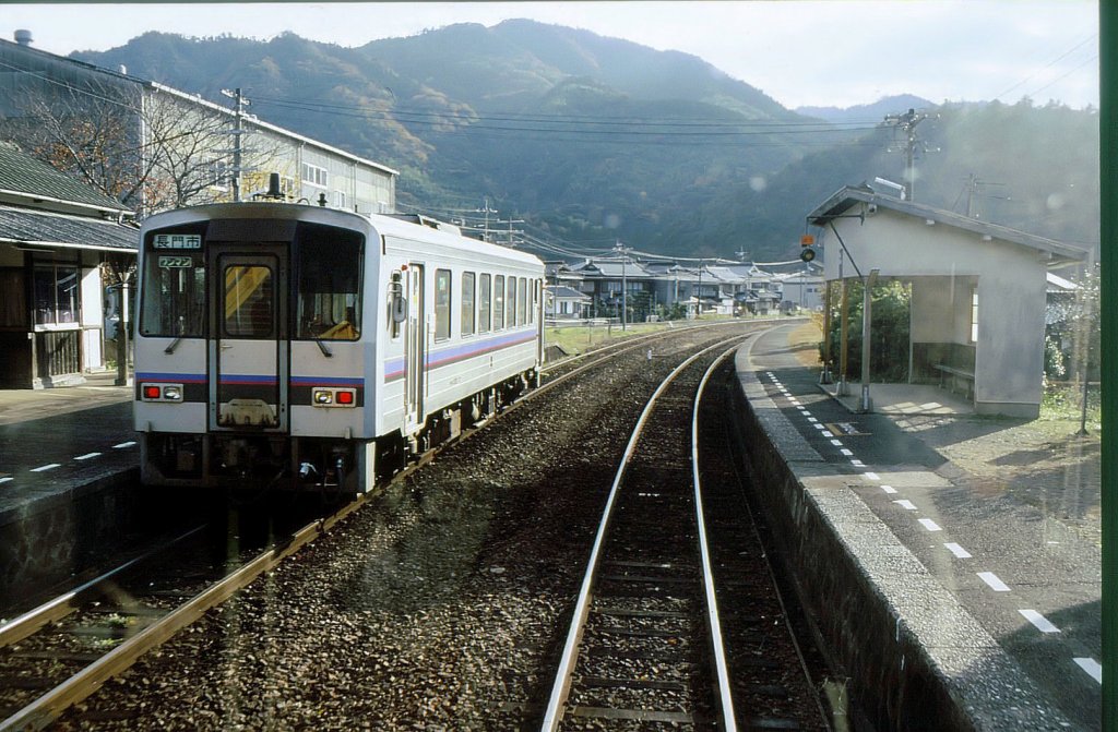 KIHA 120 (キハ１２０) auf der San-In-Linie, der Hauptstrecke entlang des Japanischen Meeres. Hier auf der dem asiatischen Kontinent zugewandten Seite Japans, wo es viel regnet und schneit, wohnen immer weniger Menschen. So genügt für den Lokalverkehr heute dieser kleine Wagen, der nur Längssitze aufweist und grau/lila Streifen hat. KIHA 120-17 in Sanmi, 3.Dezember 2005.