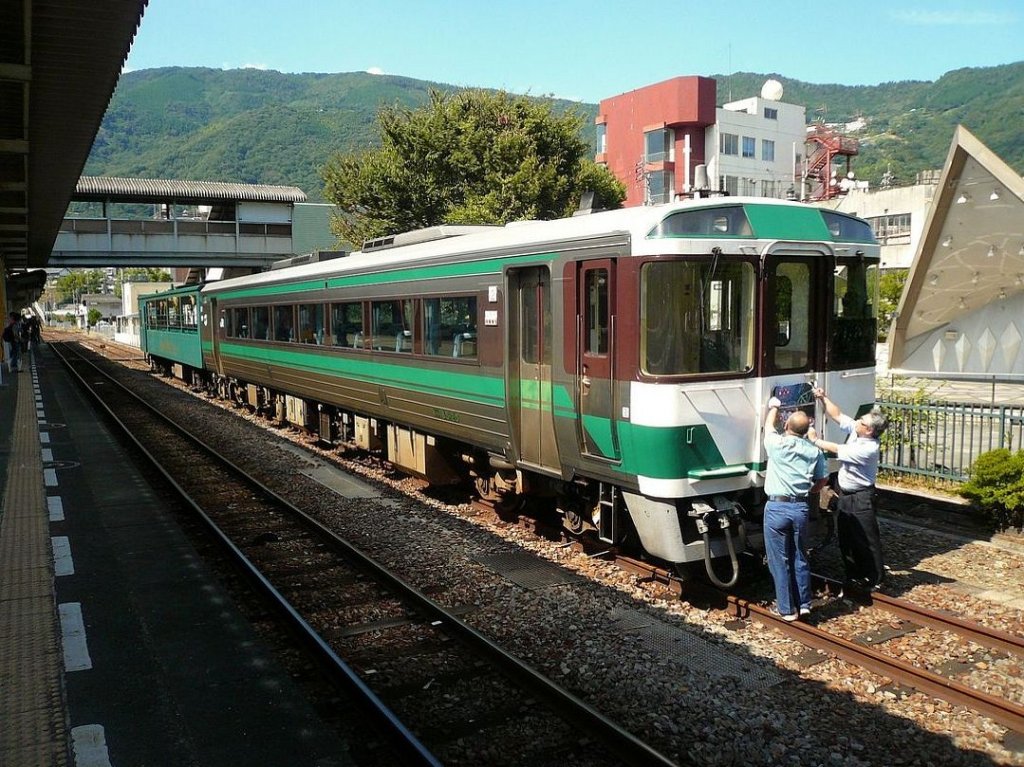 KIHA 185: Zwei Triebwagen wurden für den Touristikverkehr auf der Insel Shikoku mit einem offenen, fensterlosen Steuerwagen hergerichtet. Hier bringt das Personal gerade die Fronttafel für einen Touristenzug an Wagen KIHA 185-20 an. Awa Ikeda, 21.September 2009. 
