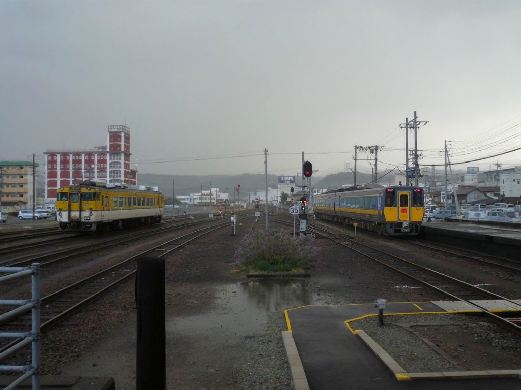 KIHA 187: Ausfahrt in den wilden Sturm. Die Fahrgäste wurden gewarnt, dass der Zug wegen Wirbelwind die nächste Stadt möglicherweise nicht erreichen kann. Zug KIHA 187-1005 + KIHA 187-5, Masuda, 3.Dezember 2010. Links ein abgestellter Lokaltriebwagen KIHA 40.  