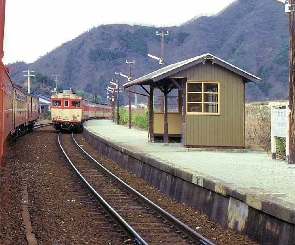 KIHA 58: Typisch 1970er Jahre - ein langer Bummelzug aus bunt gemischten Dieseltriebwagen wartet die Kreuzung mit einem Schnellzug (geführt von KIHA 58 78) ab. Heute ist die Strecke längst elektrifiziert. Bitchû Kawamo, 3.Januar 1978. 
