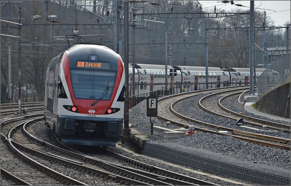 KISS 511 019 bei der Ausfahrt aus Schaffhausen wird den krzesten Weg nach Zrich nehmen, also ber Deutschland. Die beiden Gleise rechts gehen nach Basel, auch ber Deutschland, und gehren der DB, Nachfolgerin der badischen Staatsbahn. Mrz 2013.
