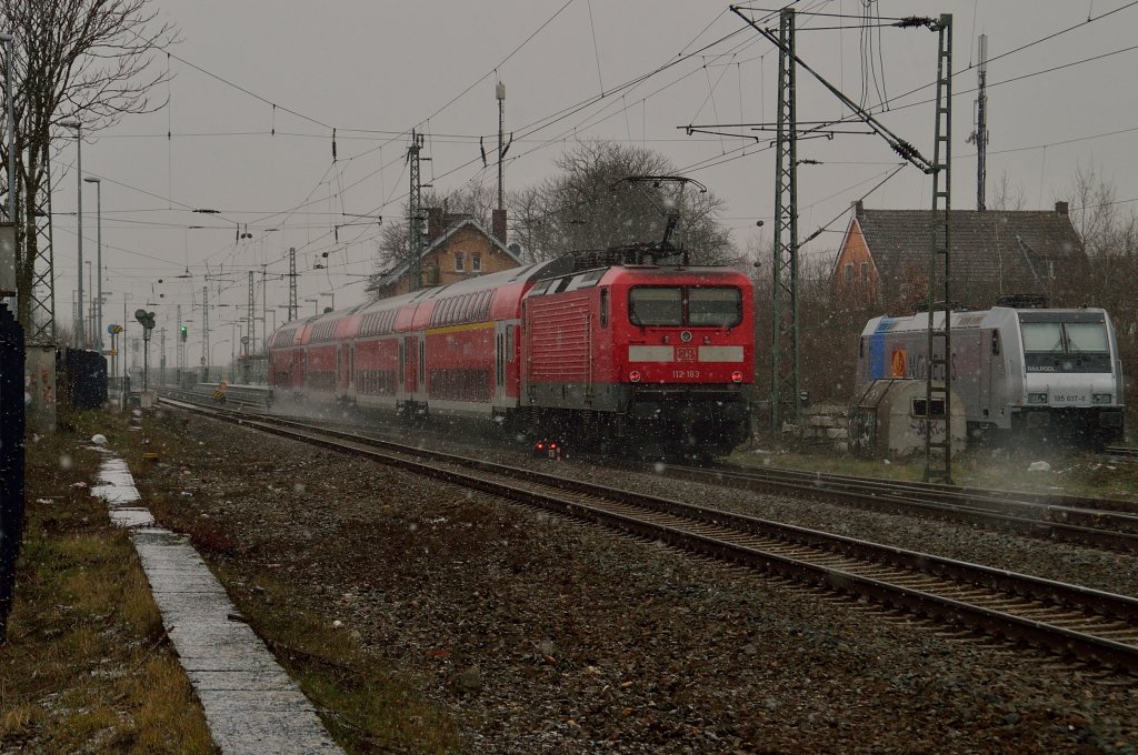 Langsam wird es immer dunkeler am Himmel und der Schneefall immer heftiger, da beeilt sich die 112 163 mit ihrem RE7 Zug nach Krefeld zu kommen und eilt mit hoher Geschwindigkeit durch Nievenheim...auf dem Abstellgleis hat sich die 185 697-0 von Railpool zum Feierabend aufgestellt..... Samstag den 23.2.2013