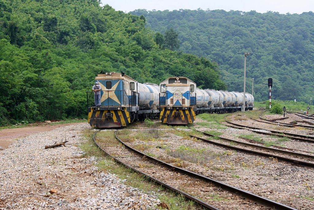 Links die TPIPL 33-003 (ex CK5 004), mit einem Zementwagenzug von der Anschlußbahn kommend, neben der TPIPL 33-005 (ex CK5 006) am 23.August 2010 in der Hin Lap Station.