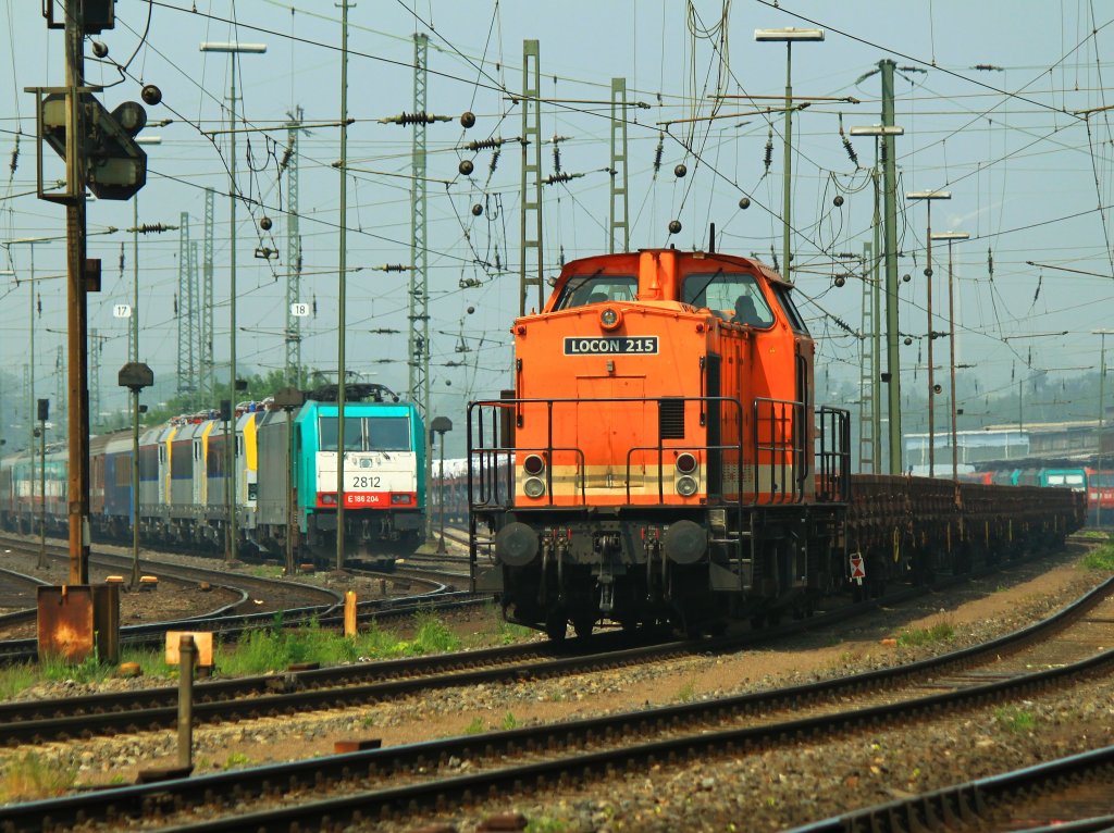 Locon 215 mit einem leeren Flachwagenzug am 23.05.2012 in Aachen West. Links im Hintergrund Cobra 186 204 (2816) mit drei neuen Siemens Eurosprinter (1877, 1889 und 1861), zwei Schutzwagen und ein neuer AM08 Triebzug. Das neue Rollmaterial wird ber die Montzenroute nach Belgien gebracht. 