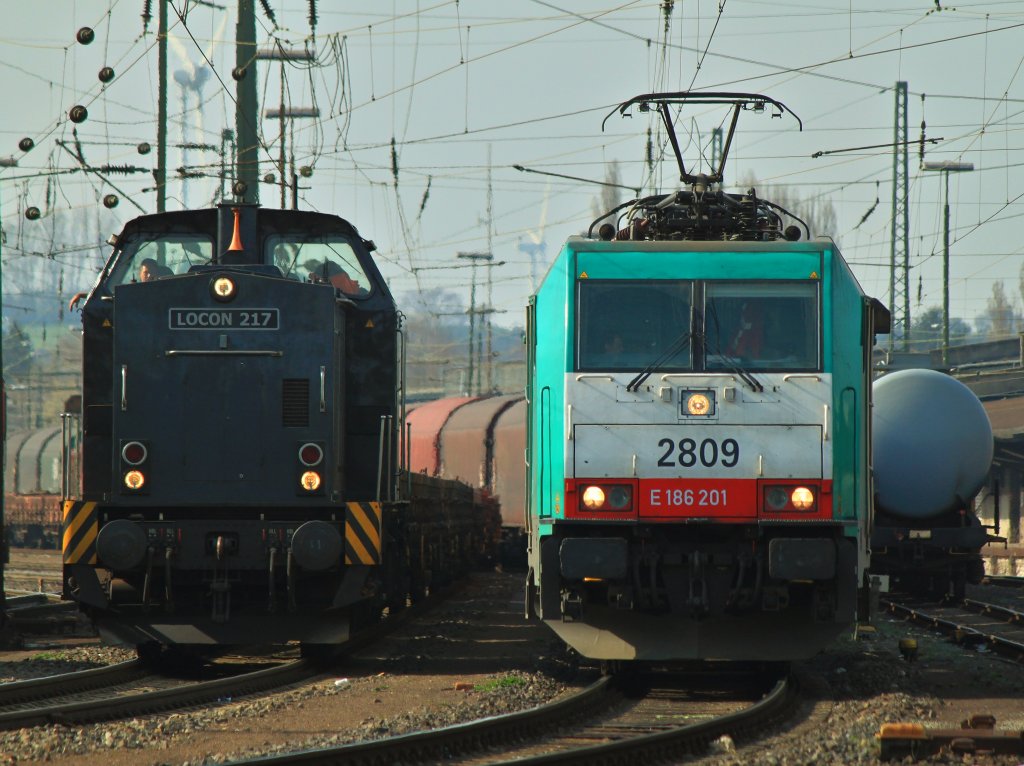 Locon 217 (203 123-5) steht am 27.03.2012 mit einem mit alten Gleisschotter beladenen Niederbordwagenzug neben Cobra 186 201 (2809), die einen Coil-Zug aus Belgien am Haken hat in Aachen West. Beide Zge warten auf Abfahrt Richtung Kln.